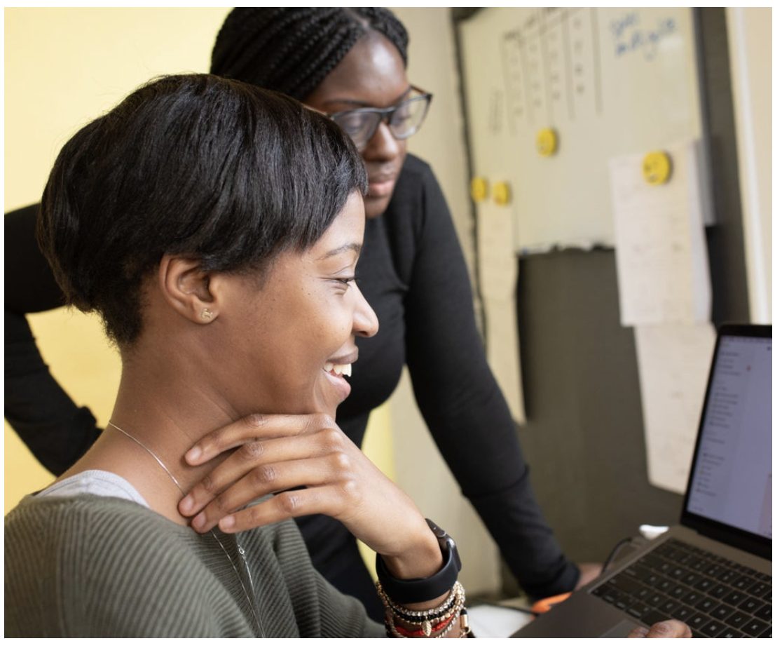 Two colleagues reviewing work together on a laptop in an office